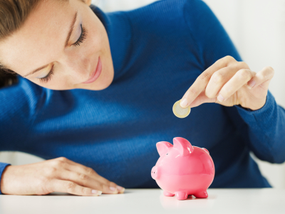 woman putting coins into a piggy bank
