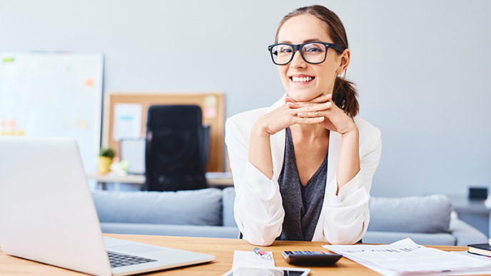 Woman smiling and sitting next to laptop