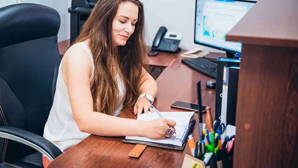 Woman sitting at desk and taking notes